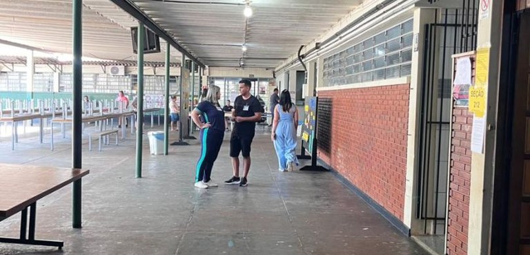 Eleições suplementares elegem novos prefeitos de três municípios paranaenses neste domingo (5 Fotografia em que se veem algumas pessoas em um pátio coberto de escola.