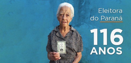 Eleitora de 116 anos tira o primeiro título em Londrina Imagem de fundo azul com uma senhora no centro segurando sua identidade. À direita,, escrito em ...
