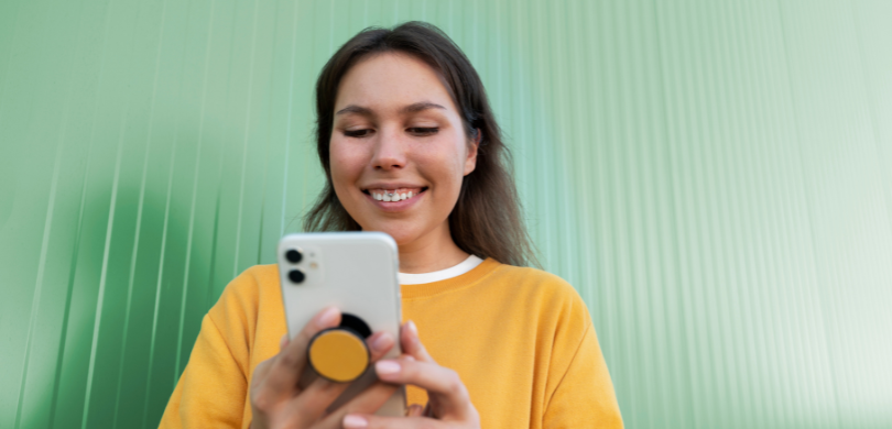 Fotografia que retrata uma mulher jovem, de pele clara e cabelos castanhos, sorrindo enquanto ut...