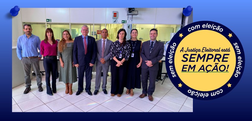 Fotografia em que aparecem várias pessoas, entre homens e mulheres, posando em pé em uma sala co...