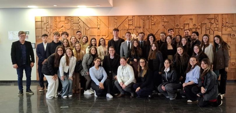 Estudantes da CESUL realizam visita acadêmica ao TRE-PR Fotografia de diversas pessoas, entre homens e mulheres, posando sorrindo no hall de entrada do ...