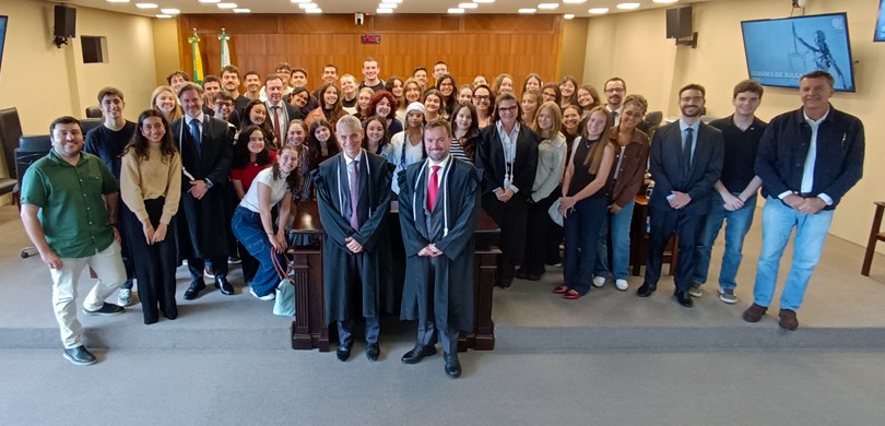 Fotografia que retrata um grande grupo de pessoas, majoritariamente jovens entre homens e mulher...