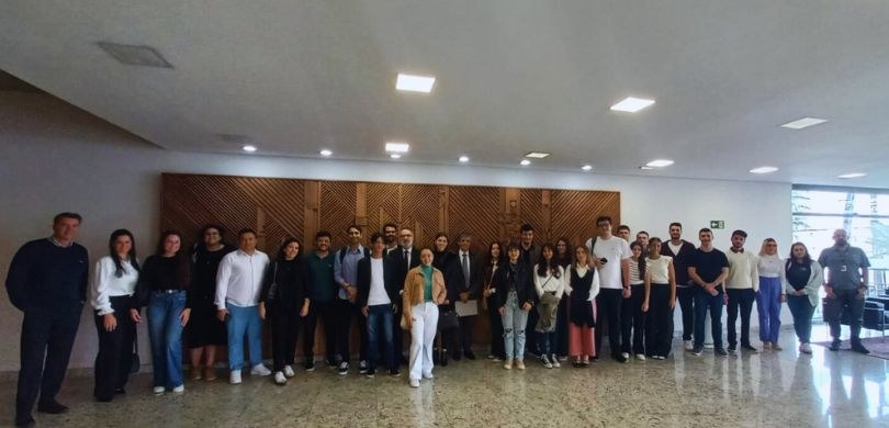 Fotografia de diversas pessoas, entre homens e mulheres, posando sorrindo no hall de entrada do ...
