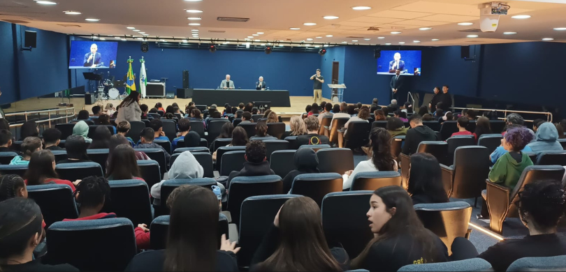 Fotografia tirada a partir da perspectiva do público em um auditório amplo, focado em direção ao...