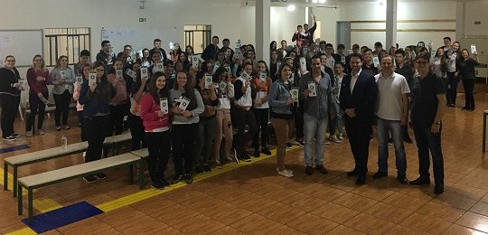 Estudantes de Manoel Ribas aprendem sobre segurança das urnas Fotografia de um grupo de pessoas dentro de uma sala de aula. Elas estão em pé e olham em direçã...