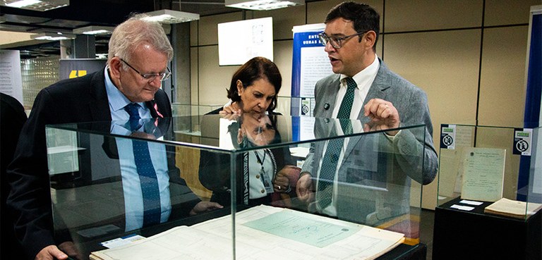 Exposição no Arquivo Público do Paraná celebra os 80 anos da reinstalação do TRE-PR Fotografia em que se veem o presidente Sigurd, a diretora Solange e o servidor Daniel observando...