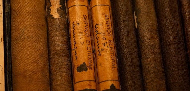 Exposição no Arquivo Público do Paraná celebra os 80 anos da reinstalação do TRE-PR Fotografia em que se veem lombadas de livros antigos da Justiça Eleitoral do Paraná.