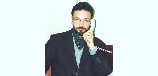 Fernando tomou posse em 1º de julho de 1989 no TRE-PR Fotografia antiga de um homem de terno e gravata falando em um telefone fixo em frente a uma par...