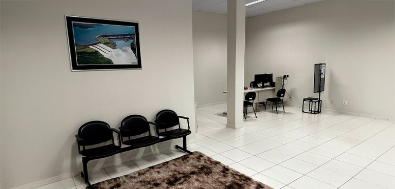 Fotografia da sala calma de Foz do Iguaçu. O local tem parede e piso brancos, comum guichê de at...