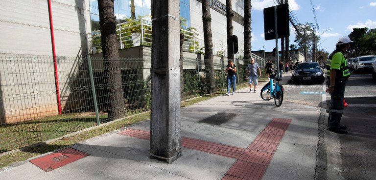 Foto de uma calçada acessível, com piso tátil, em frente ao prédio do Fórum Eleitoral de Curitiba.
