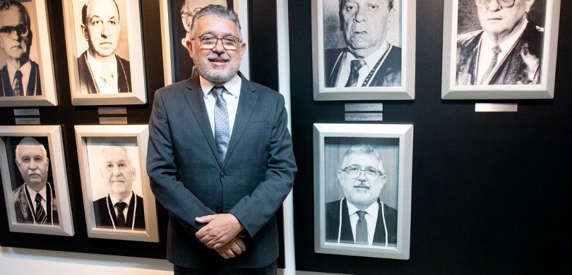 Presidente do TRE-PR posando à frente da galeria dos ex 1º vice-presidentes do TJPR