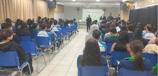Fotografia de cinco pessoas, quatro homens e uma mulher, em uma sala clara. Dois rapazes com col...