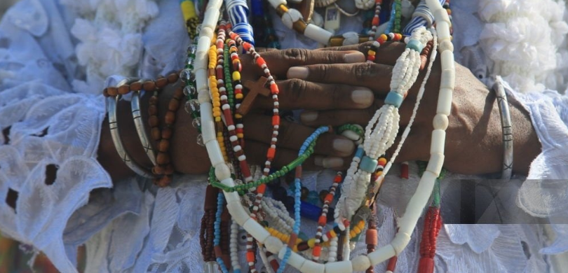 Fotografia de uma pessoa negra, cujo rosto não é possível identificar, com as mãos unidas em dir...
