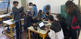 Fotografia de um grupo de jovens estudantes reunidos em uma sala de informática.