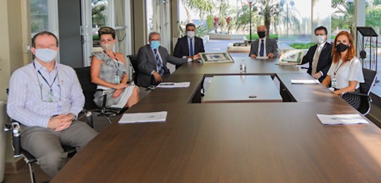 Fotografia de um grupo de pessoas sentadas ao redor de um mesa