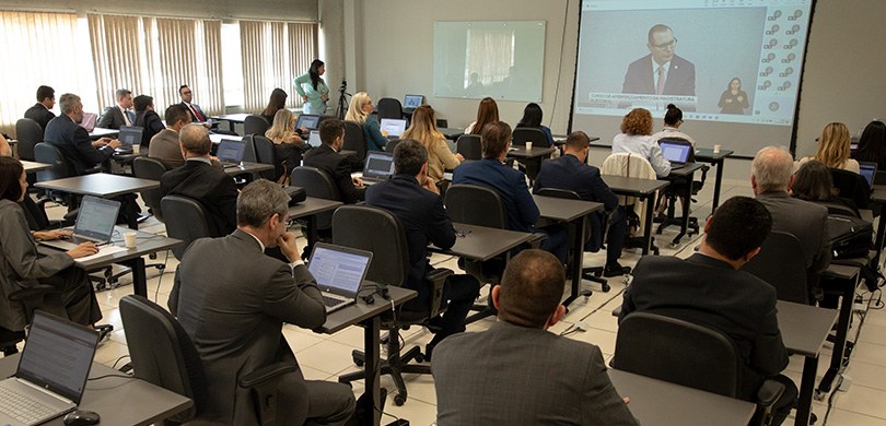 Juízes eleitorais participam da segunda aula presencial do curso de aperfeiçoamento 1 Fotografia de diversas pessoas, entre homens e mulheres, sentados em cadeiras com estofado preto...