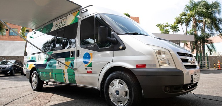 Fotografia que retrata uma van modelo Ford Transit de cor prata, adaptada para atendimento itine...