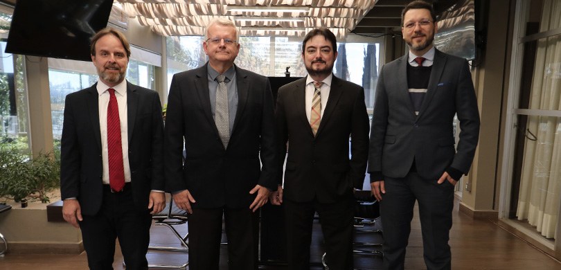 Fotografia em que aparecem quatro homens vestindo ternos escuros. Eles posam no terraço da Presi...