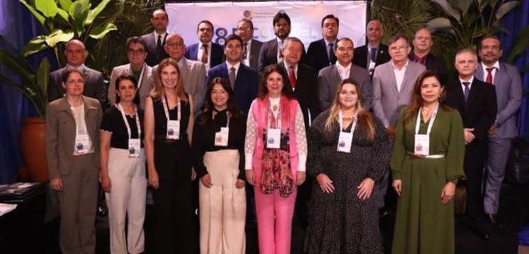 Fotografia de diversas pessoas posando sorrindo, organizadas em três fileiras. Na primeira filei...