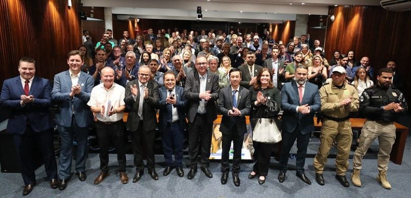 Fotografia em que aparecem diversas pessoas em pé, no Plenarinho da Assembleia Legislativa do Pa...
