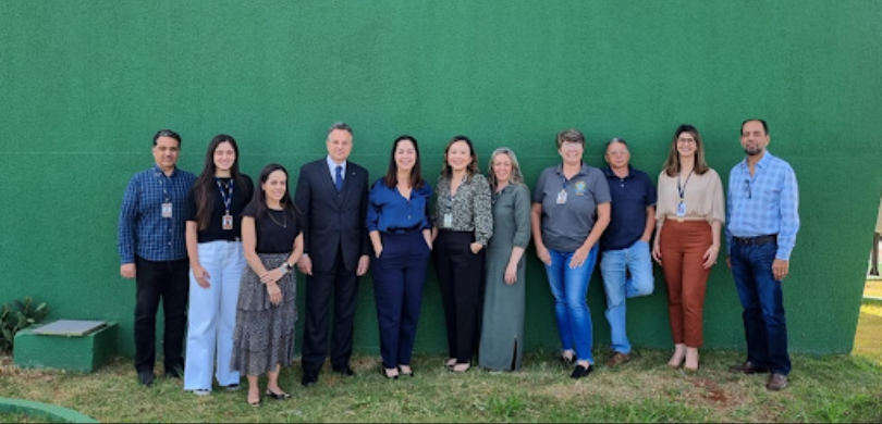 Fotografia de 11 pessoas, entre homens e mulheres, posando sorrindo em frente ao Fórum Eleitoral...