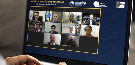 Live da Escola Judiciária Eleitoral do Paraná discutiu participação de minorias no processo eleitoral Imagem de um notebook exibindo a tela do evento on-line. Na tela, o fundo é azul escuro; na part...