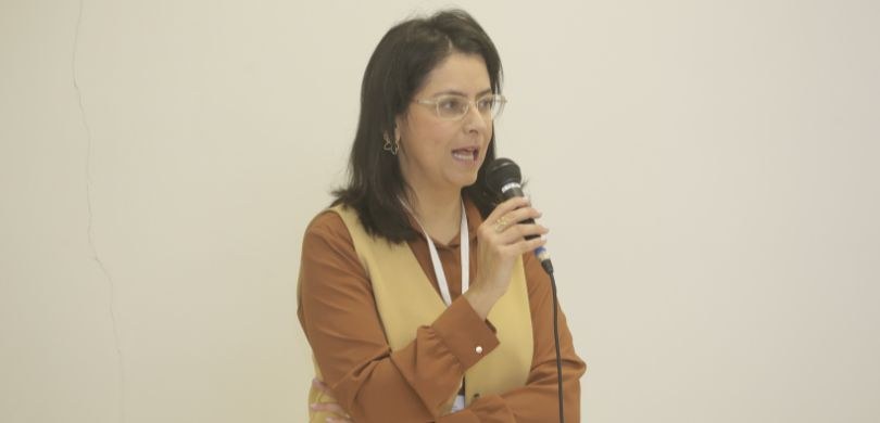 Fotografia de uma mulher de pele clara, cabelos pretos na altura dos ombros e óculos de armação ...