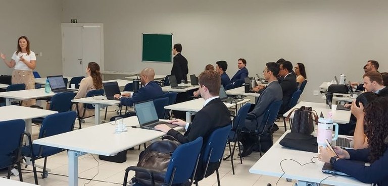 Magistrados participam do terceiro dia do curso de formação promovido pela EJE-PR 2 Fotografia de diversas pessoas, entre homens e mulheres, sentadas em carteiras azuis diante de c...