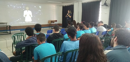 Fotografia de uma sala de aula, com jovens assistindo a apresentação de um vídeo da Justiça Elei...