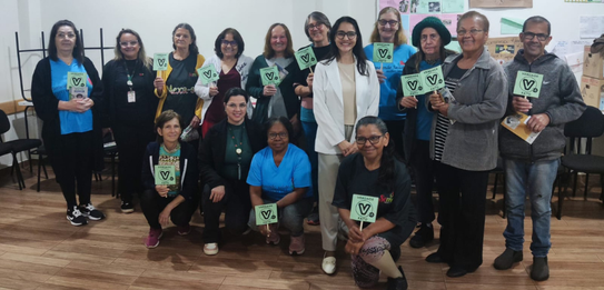 Fotografia de cinco pessoas, quatro homens e uma mulher, em uma sala clara. Dois rapazes com col...