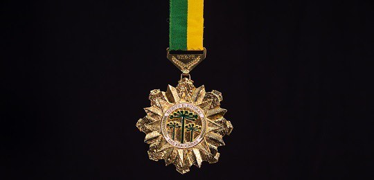 Foto da medalha do Mérito Eleitoral das Araucárias em um fundo preto
