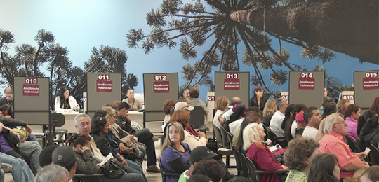 Foto de pessoas sentadas em cadeiras aguardando o atendimento na Central de Atendimento ao Eleit...
