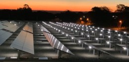 Na fotografia, há vários painéis fotovoltaicos uns ao lado dos outros.  Ao fundo, no horizonte, ...
