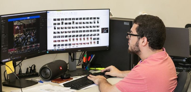 O jovem Rafael aparece trabalhando sentado, de perfil, olhando para a tela de um computador. Ele...