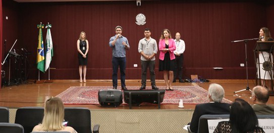 No Paraná, gestores e servidores discutem melhorias no processo eleitoral Foto de algumas pessoas no palco do auditório do TRE-PR