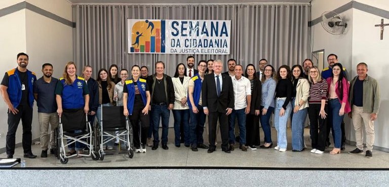 Fotografia em que aparecem várias pessoas, algumas usando coletes azuis e amarelos da Justiça El...