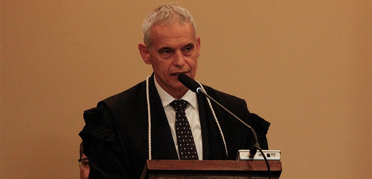 Fotografia que retrata um homem branco de cabelos curtos e grisalhos em um plano médio, do busto...