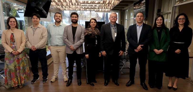 Na fotografia, há homens e mulheres posando sorrindo, um ao lado do outro. Dentre eles, está o p...