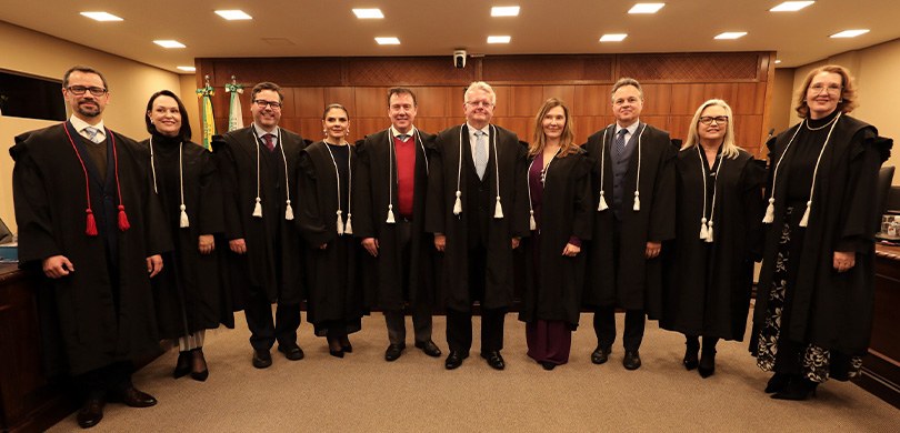 Novos membros da Corte da classe de Juiz de Direito tomam posse no TRE-PR 1 Fotografia da Corte do TRE-PR na sala de sessões, que tem piso em carpete e paredes beges, com d...