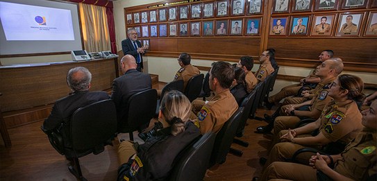 Fotografia de cinco homens sentados em uma mesa, todos eles estão vestindo terno.