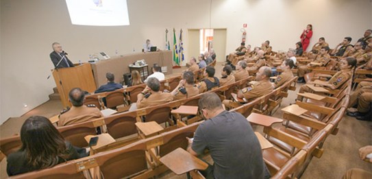 Um homem, que veste terno, está falando em um púlpito enquanto uma plateia o assiste.