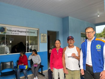 Fotografia de um grupo de indígenas sentados em uma central de atendimento ao eleitor.