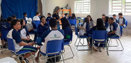 Fotografia de cinco pessoas, quatro homens e uma mulher, em uma sala clara. Dois rapazes com col...