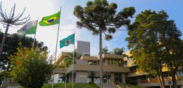 Fotografia da fachada do TRE-PR. No alto, há a bandeira do Paraná e do Brasil hasteadas.