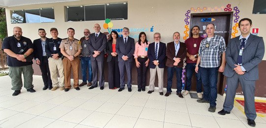 foto de um grupo de pessoas em pé, olhando para a câmera. Elas estão no pátio de uma escola 