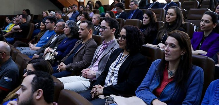 Várias pessoas sentadas nas cadeiras de um auditório.