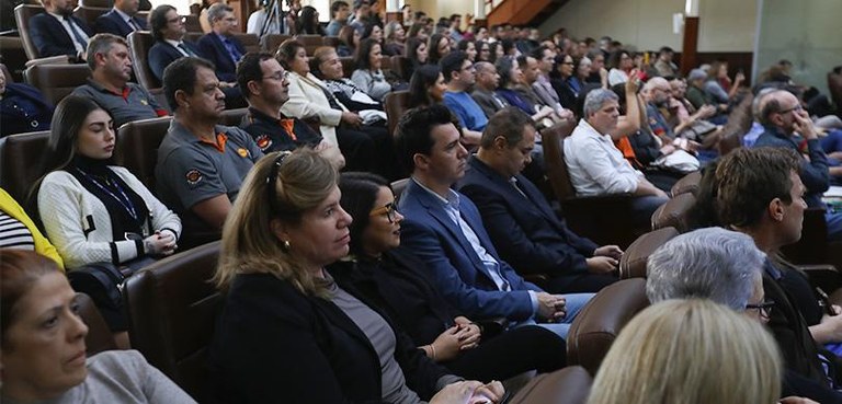 Várias pessoas sentadas nas cadeiras de um auditório.