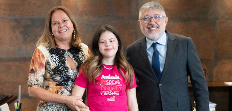 Fotografia de uma mulher loira com um vestido estampado; uma jovem com síndrome de Down com uma ...