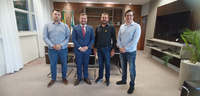 Fotografia em que se observa um grupo de quatro homens alinhados lado a lado, em pé, em um ambie...