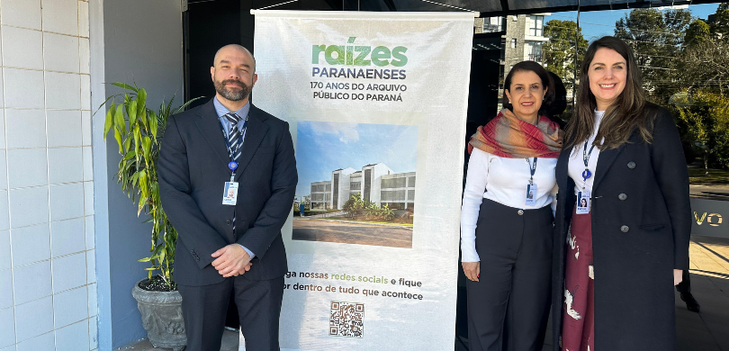 Fotografia de um homem de terno e duas mulheres, que vestem roupas de inverno nas cores preta, v...